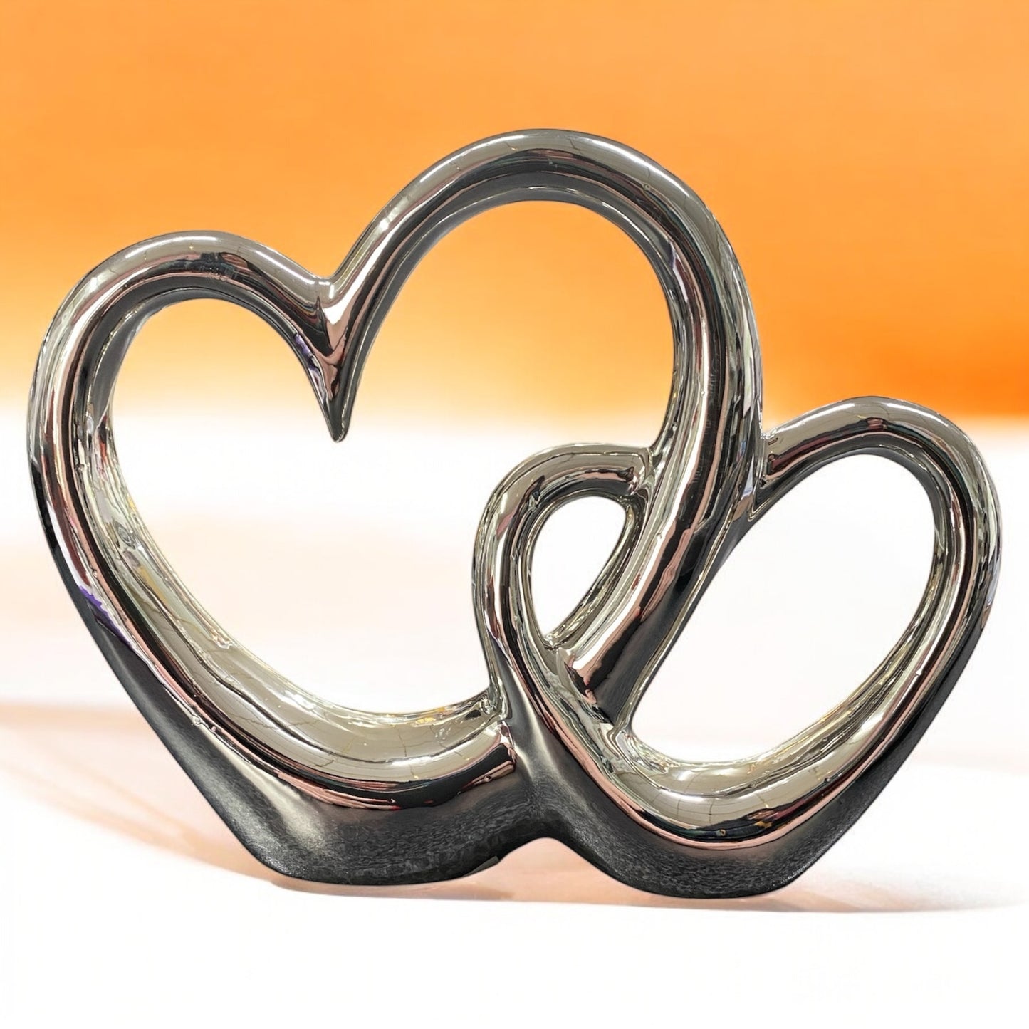 Glänzender Dekoaufsteller Doppelherz aus silberner Keramik mit zwei ineinander verschlungenen Herzen im Ambiente