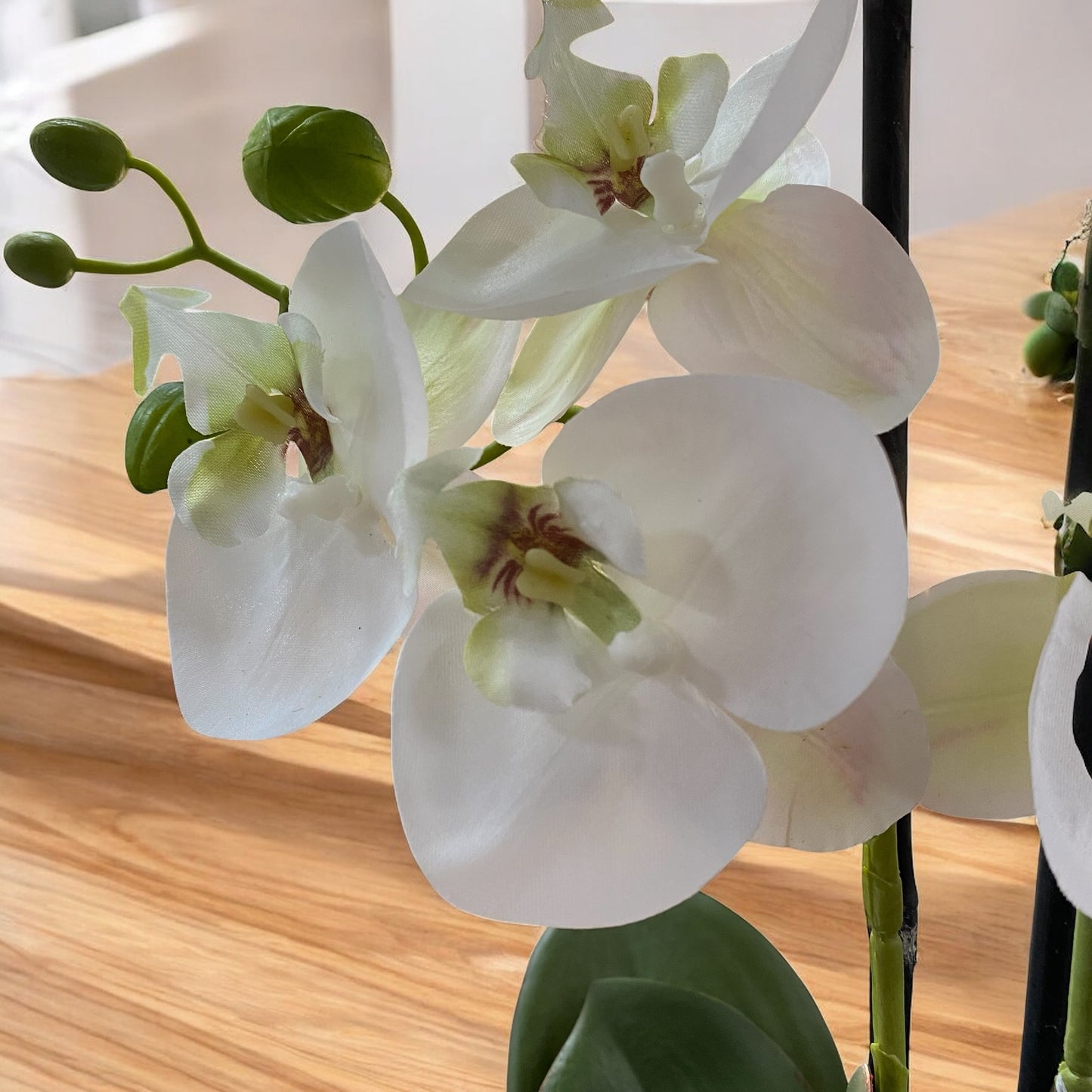 Detailaufnahme einer weißen Kunst-Orchidee mit Blüten und Knospen, täuschend echt gestaltet.