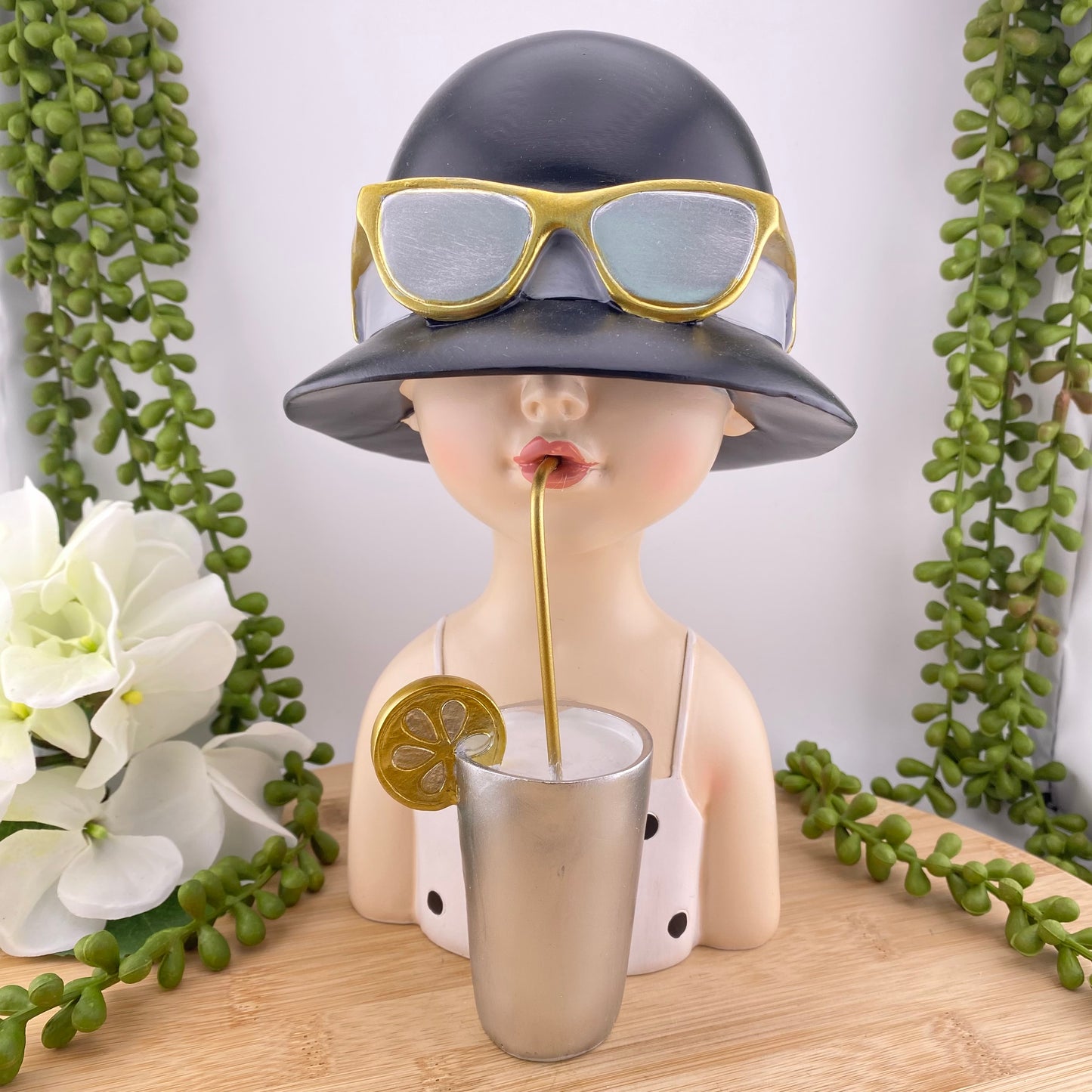 Mädchenbüste aus Kunststein mit Hut und Cocktail im Ambiente platziert