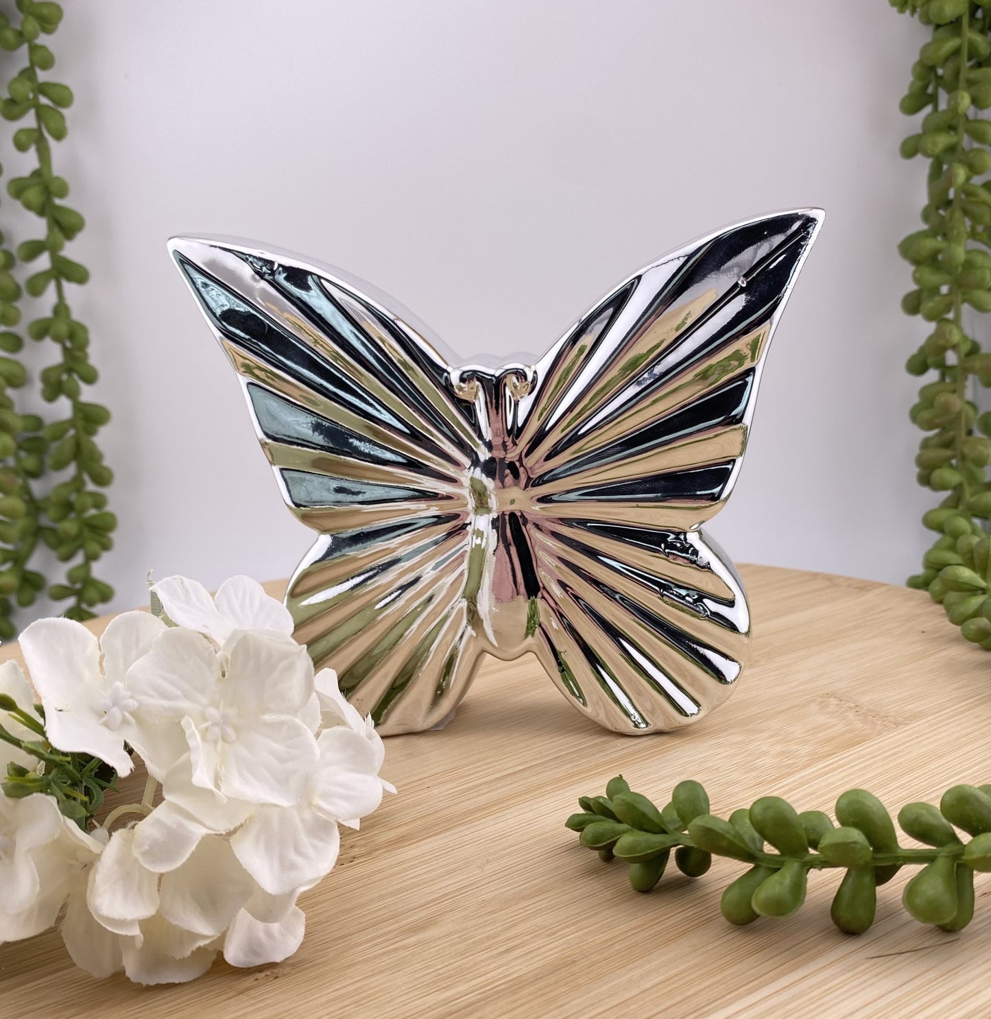 Ein silberner Deko Schmetterling im Ambiente platziert.