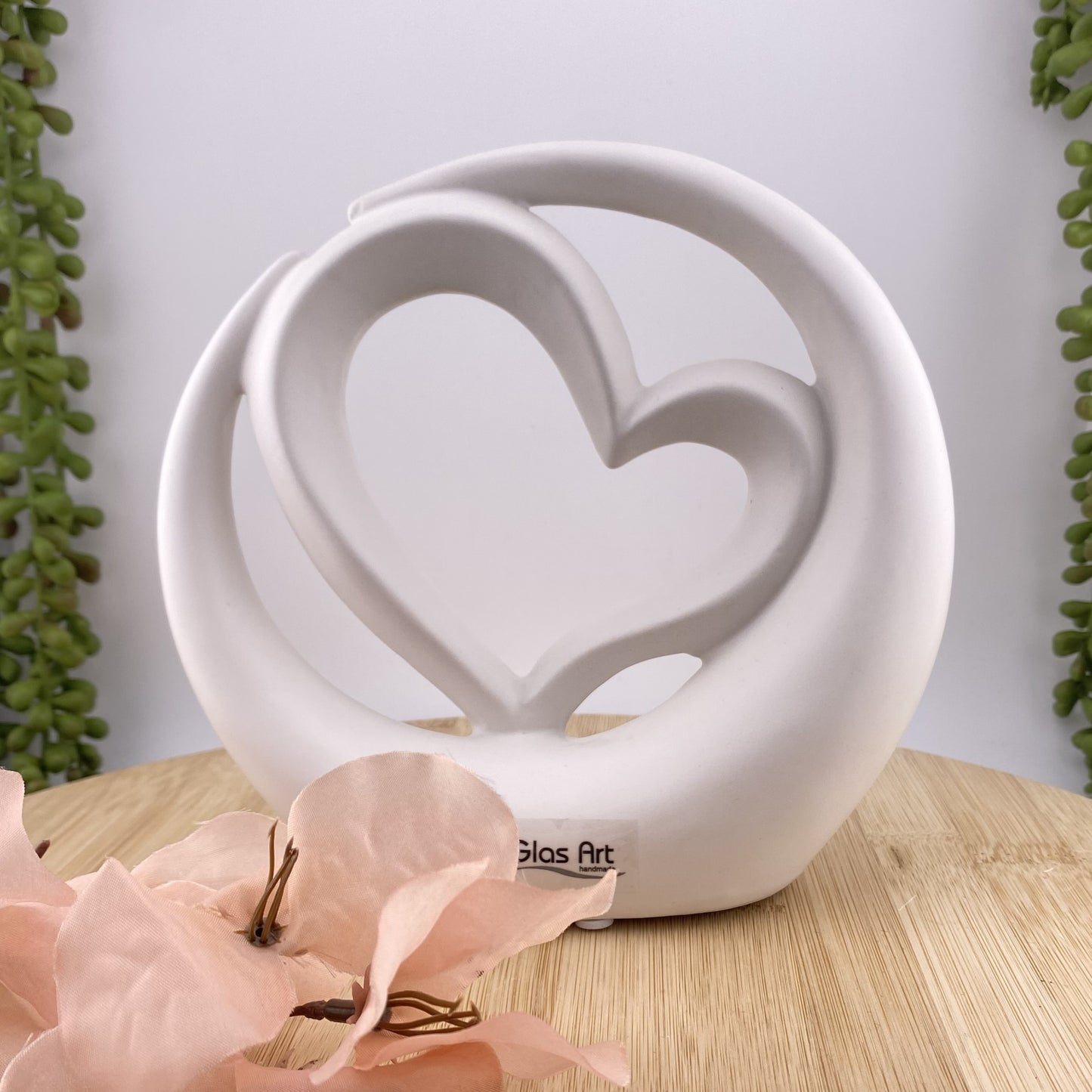 Weiße Dekofigur, die ein Herz in einem Kreis im Ambiente abbildet.