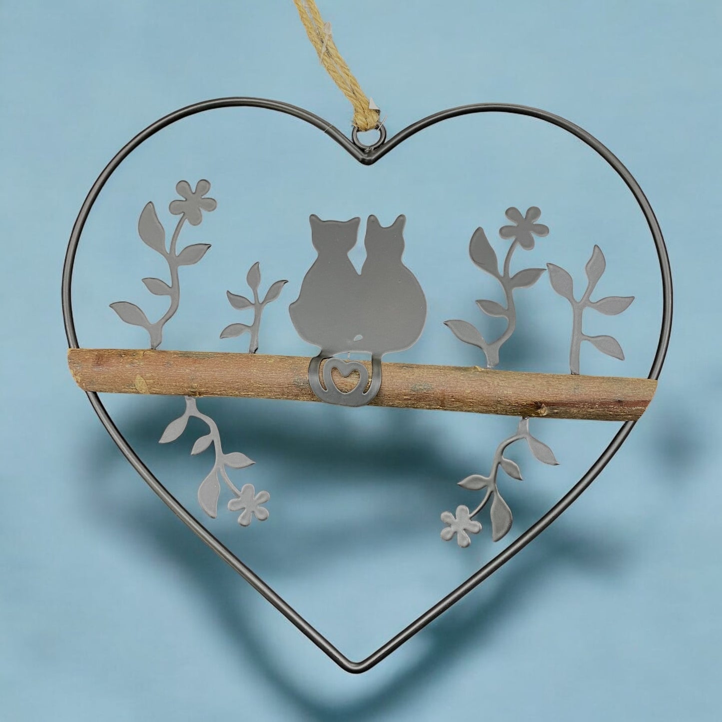 Ein Dekohänger aus einem Metall-Herz mit Katzenpaar und Holzstange als Fensterdekoration zum Aufhängen im Ambiente