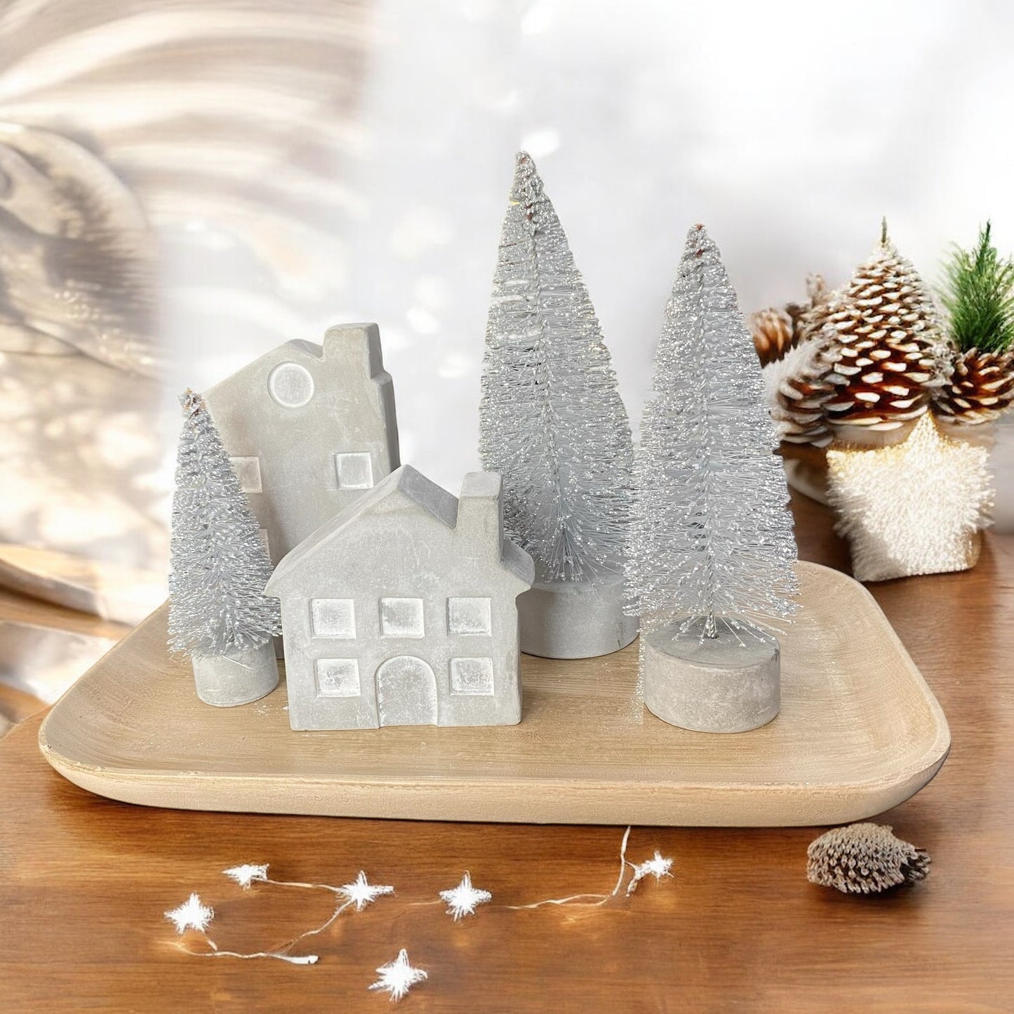Geschenkset bestehend aus 2 Betonhäusern, drei silbernen Tannenbäumen und einem Holztablett im Ambiente platziert