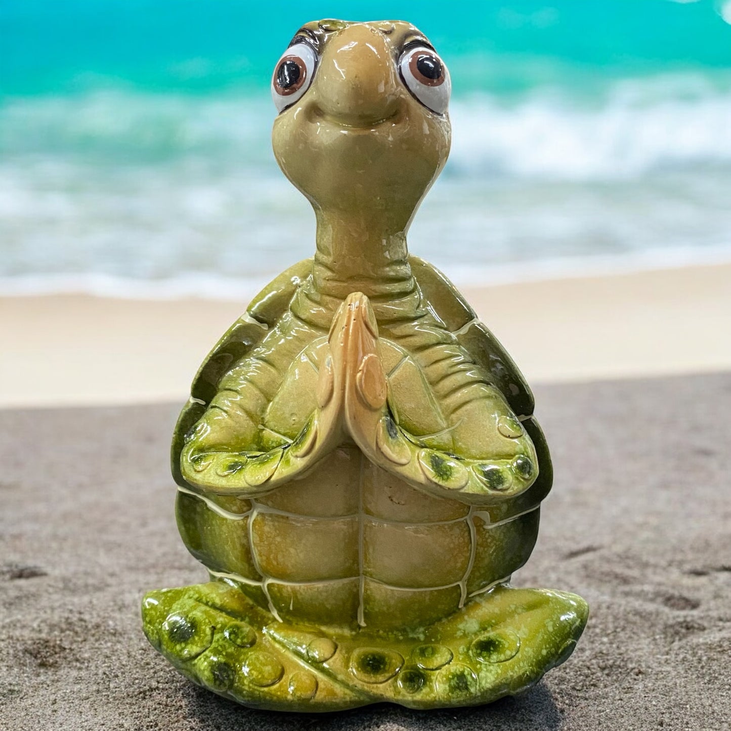 Eine grüne Schildkröte Dekofigur sitzt meditierend vor weißem Hintergrund platziert. Ihre braunen Augen sind geöffnet und sie lächeln zufriedend.