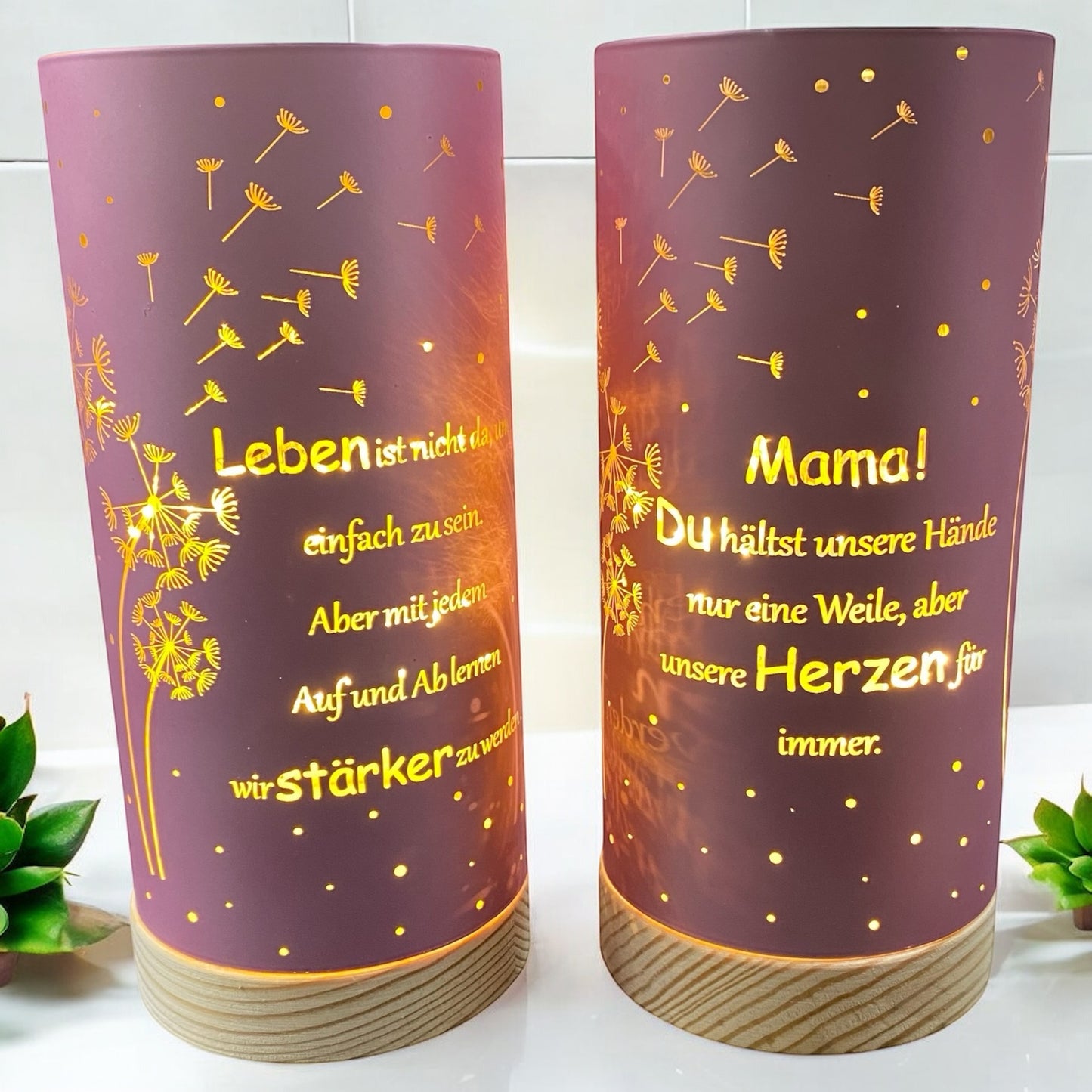 Zwei rosa LED Säulen mit Holz Sockel. Auf dem Dekolicht ist der Spruch "Leben ist nicht da, um einfach zu sein. Aber mit jedem Auf und Ab lernen wir stärker zu werden." und "Mama! Du hälst unsere Hände nur eine Weile, aber unsere Herzen für immer" und Pusteblumen abgebildet in goldener Schrift. Die Dekolichter sind im Ambiente platziert