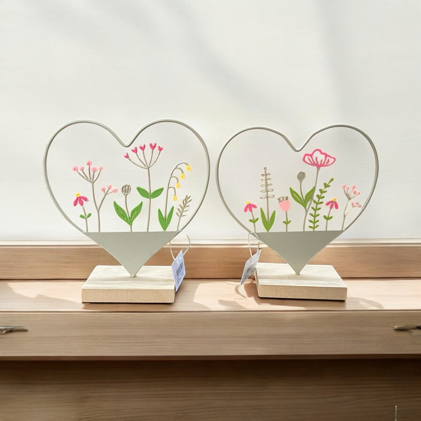 Metallherz mit Blumen in zwei Varianten auf einem Holzsockel im Ambiente platziert