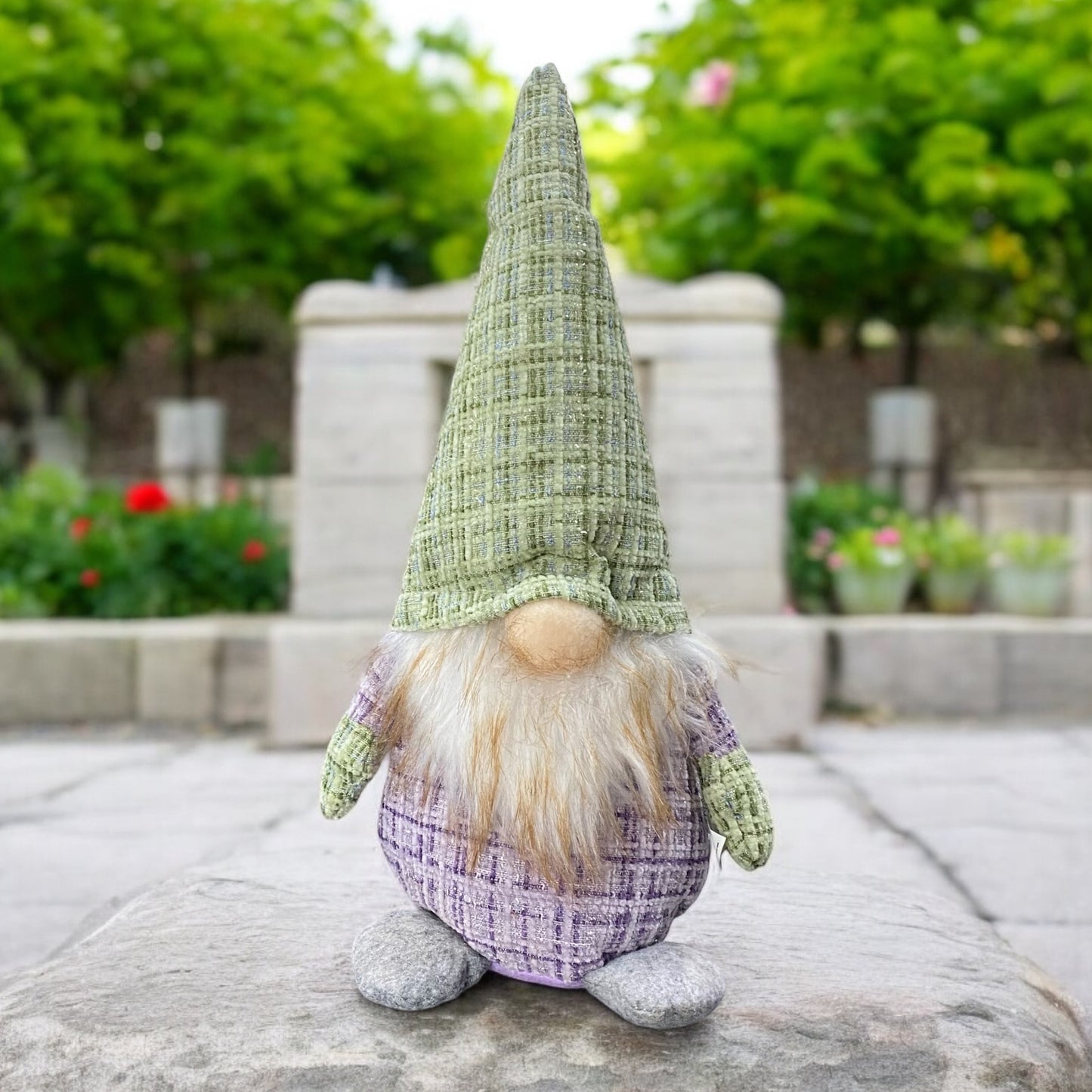 Ein großer Deko Stoff Wichtel zum Aufstellen mit grüner Zipfelmütze und lila Körper im Ambiente