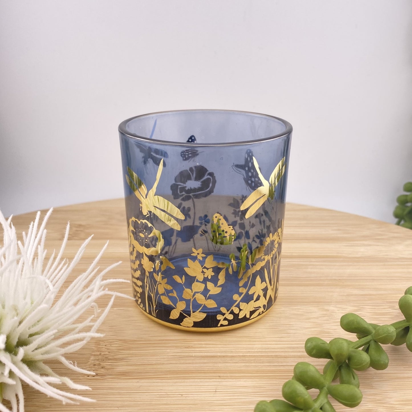 Teelichglas in blau mit goldener Malerei im Ambiente platziert