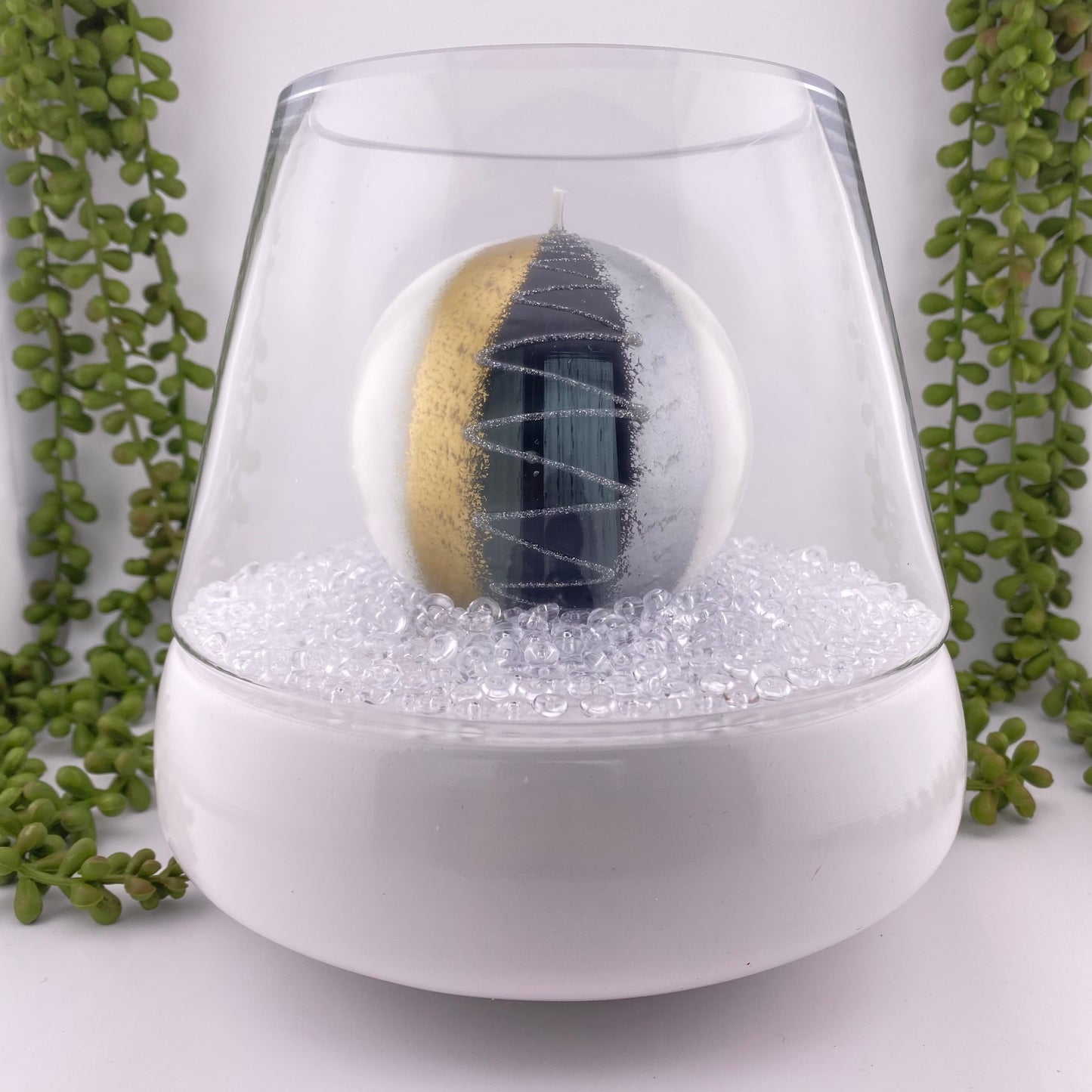 Windlicht bestehend aus weißem Keramikboden und Glasaufsatz im Ambiente platziert