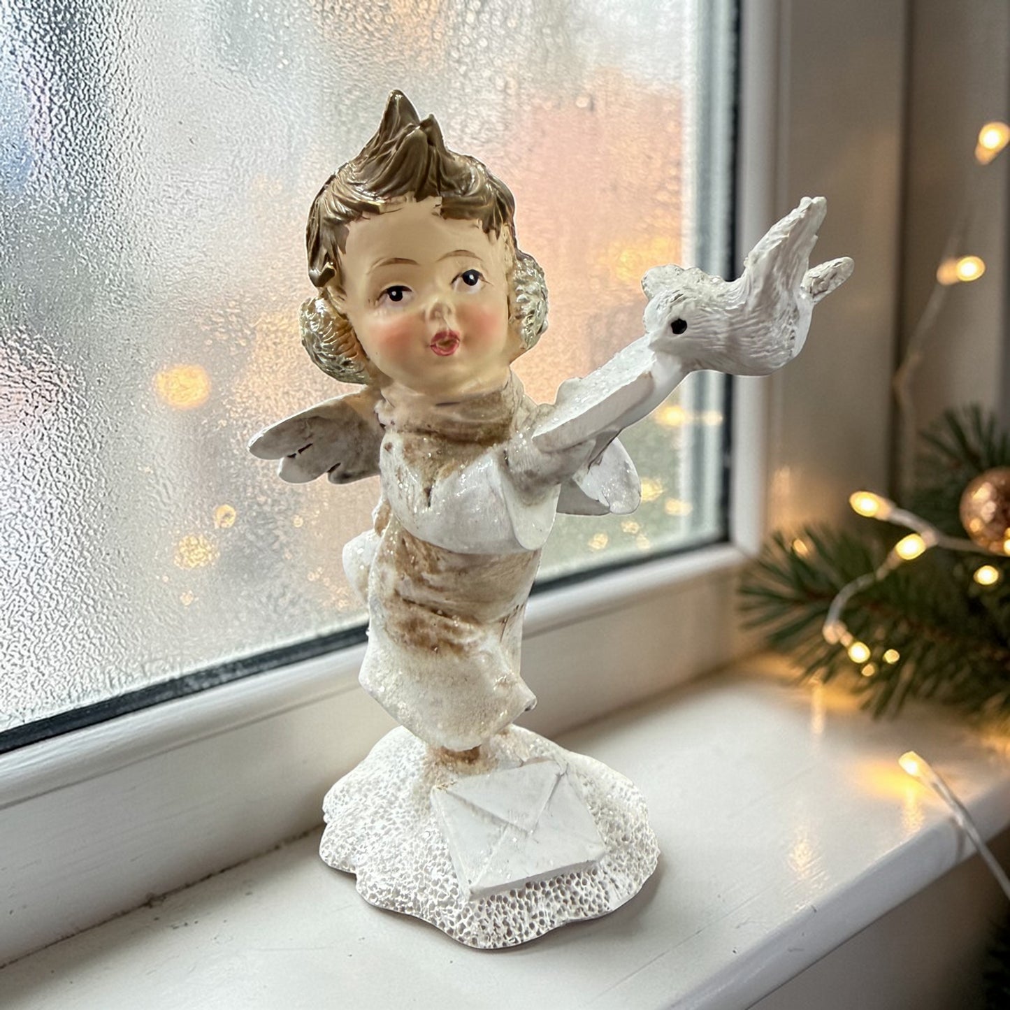 Eine dekorative Figur zeigt ein Kind mit Flügeln, das einen Vogel auf der Hand hält.