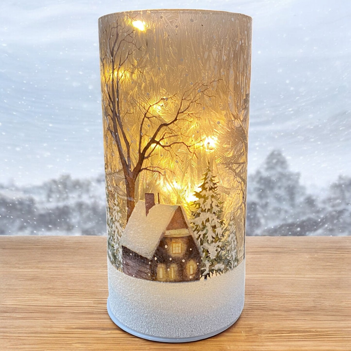 Leuchtendes Winter-LED-Deko-Licht mit verschneiter Hütte und Tannen, stimmungsvoll vor winterlichem Hintergrund präsentiert.