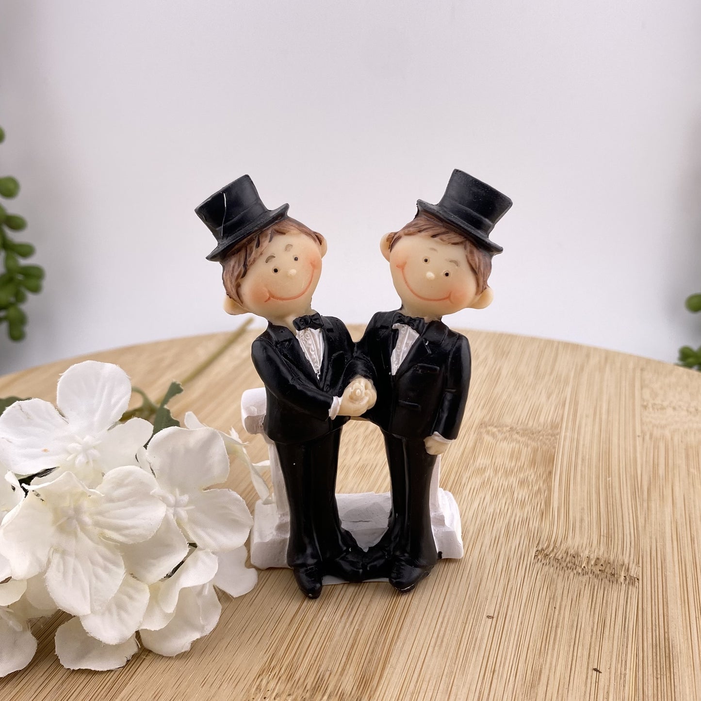 Dekofigur Aufsteller im Ambiente bildet Brautpaar zwei Männer in schwarzen Anzügen mit Hut ab. Die beiden geben sich die Hand und lächeln.