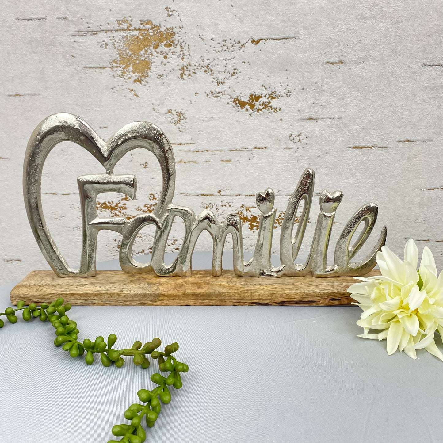 Ein Deko Holz Aufsteller mit Holzsockel und Aluminium Schriftzug Familie mit Herz im Ambiente