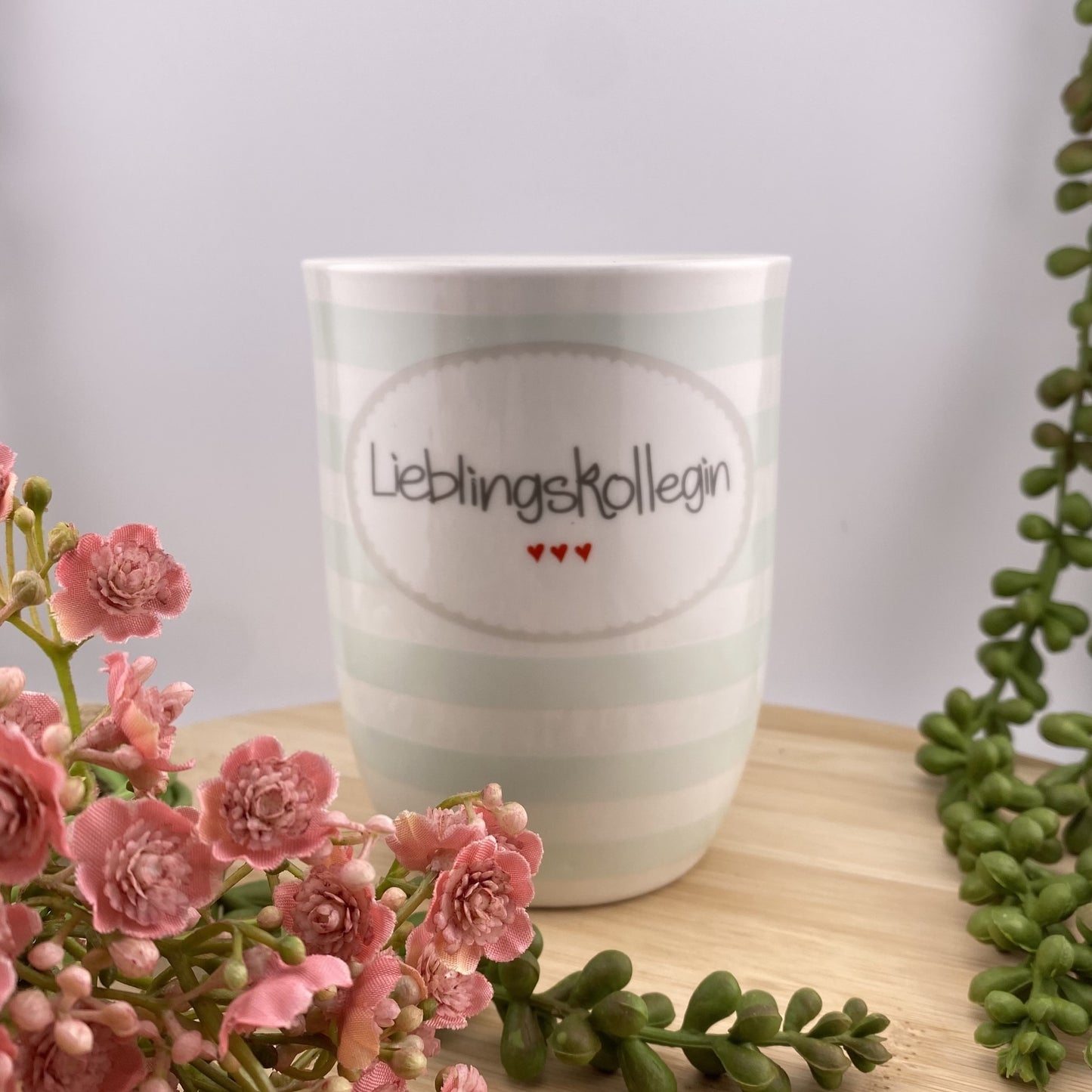 Eine türkis weiß gestreifte Kaffeetasse mit Henkel und Schriftzug Lieblingskollegin im Ambiente