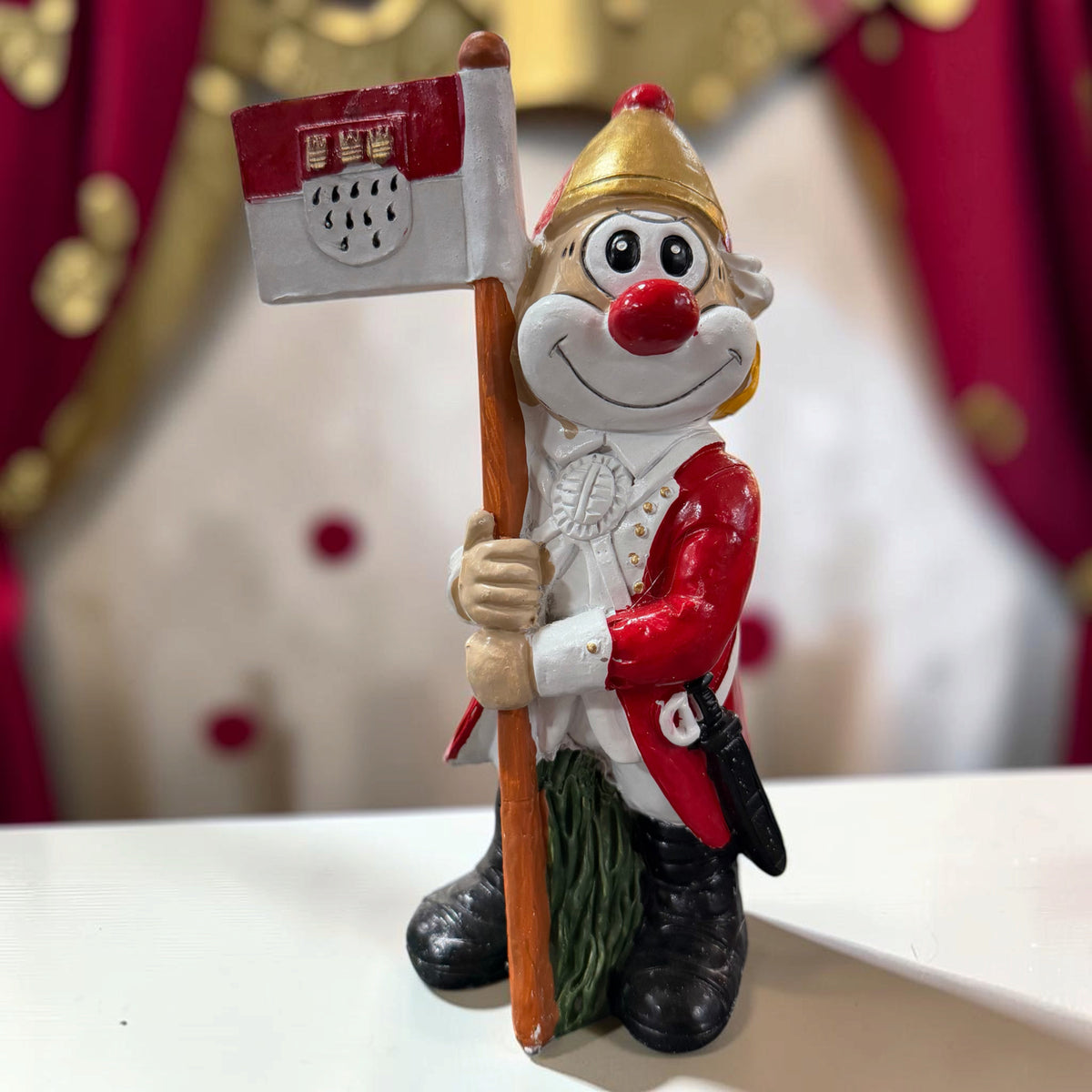 Karneval Deko Clown Die Schmitzens Fahnenträger 20 cm mit rot-weißer Fahne vor festlicher Karnevalsdekoration.