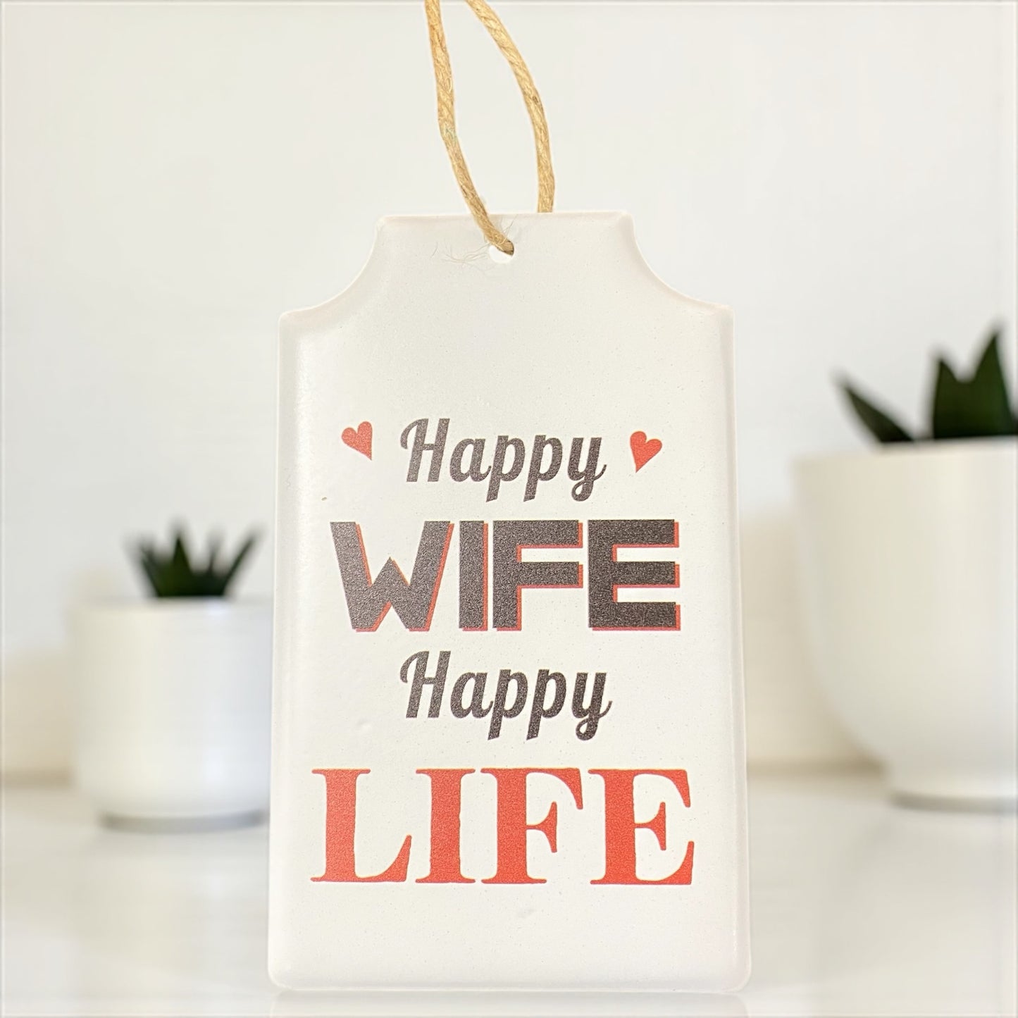 Metallschild mit Spruch „Happy Wife Happy Life“ in Weiß und Rot, dekoratives Schild mit Herzmotiven und Kordel zum Aufhängen im Ambiente.