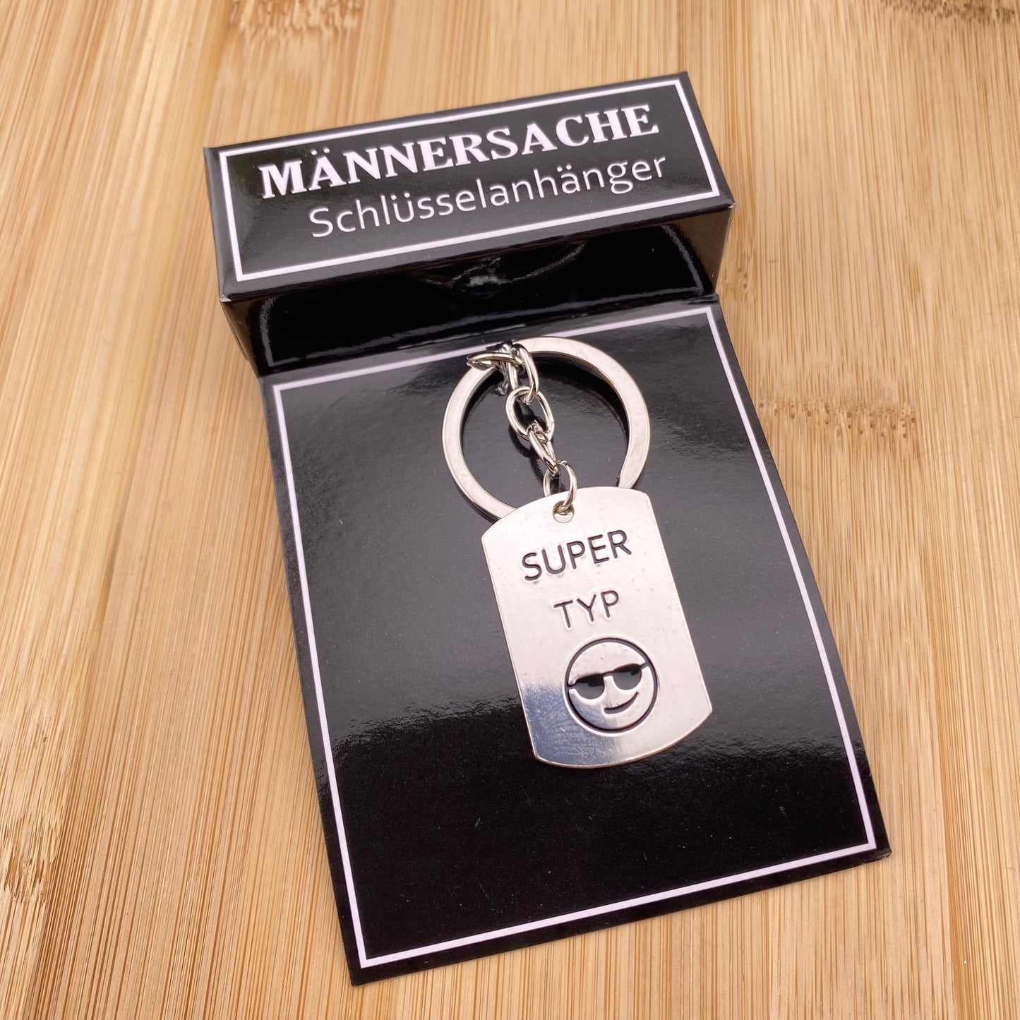 Ein silberner Schlüsselanhänger mit Schriftzug Super Typ im Ambiente