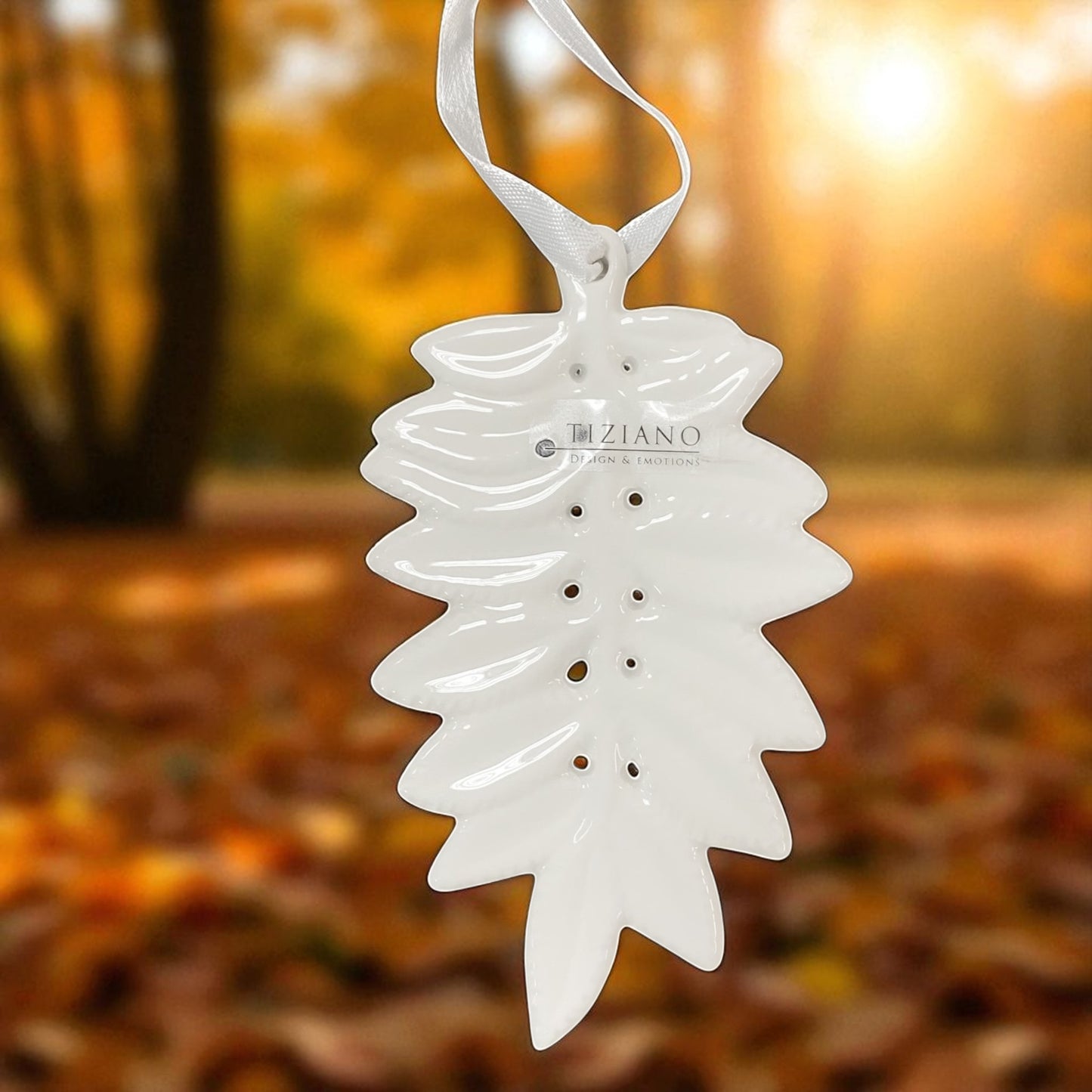 Detailansicht von weißem Keramik Hänger in Blattform mit dekorativen Lochungen und satinweißen Aufhängebändern im Ambiente