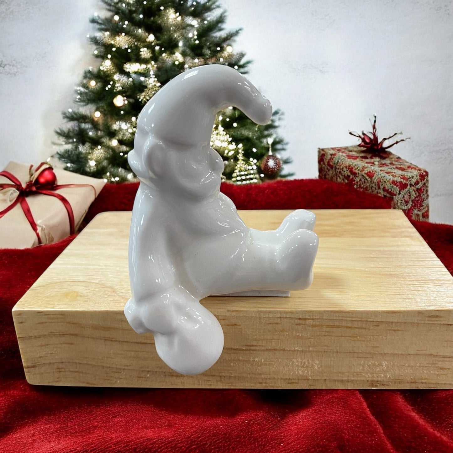 Tiziano Santa Linus sitzend, weiße Keramikfigur mit Mütze, weihnachtlicher Kantensitzer vor festlicher Kulisse.