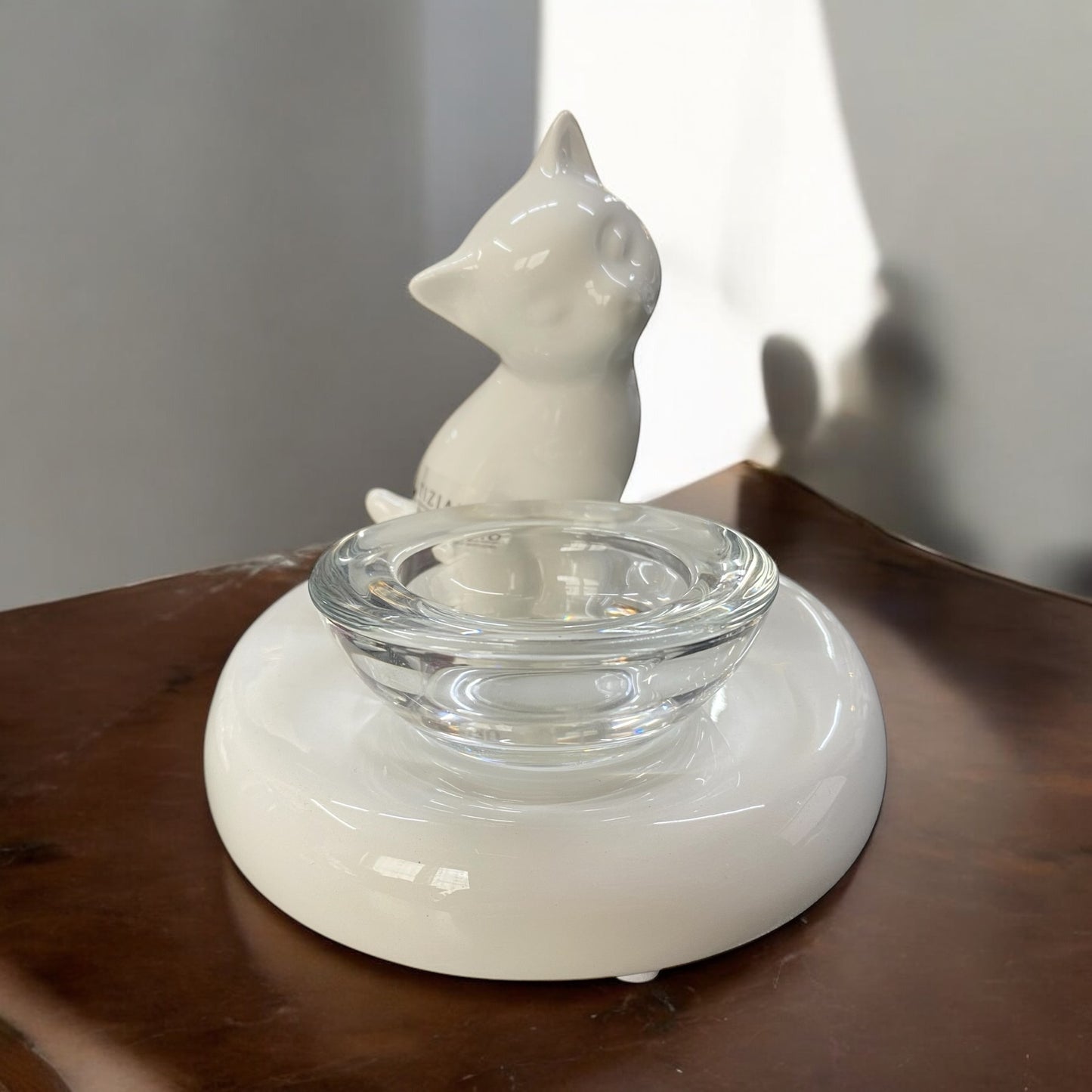 Teelichthalter mit einer kleinen Katze aus cremeweißer Keramik und einem Glasaufsatz im Ambiente platziert