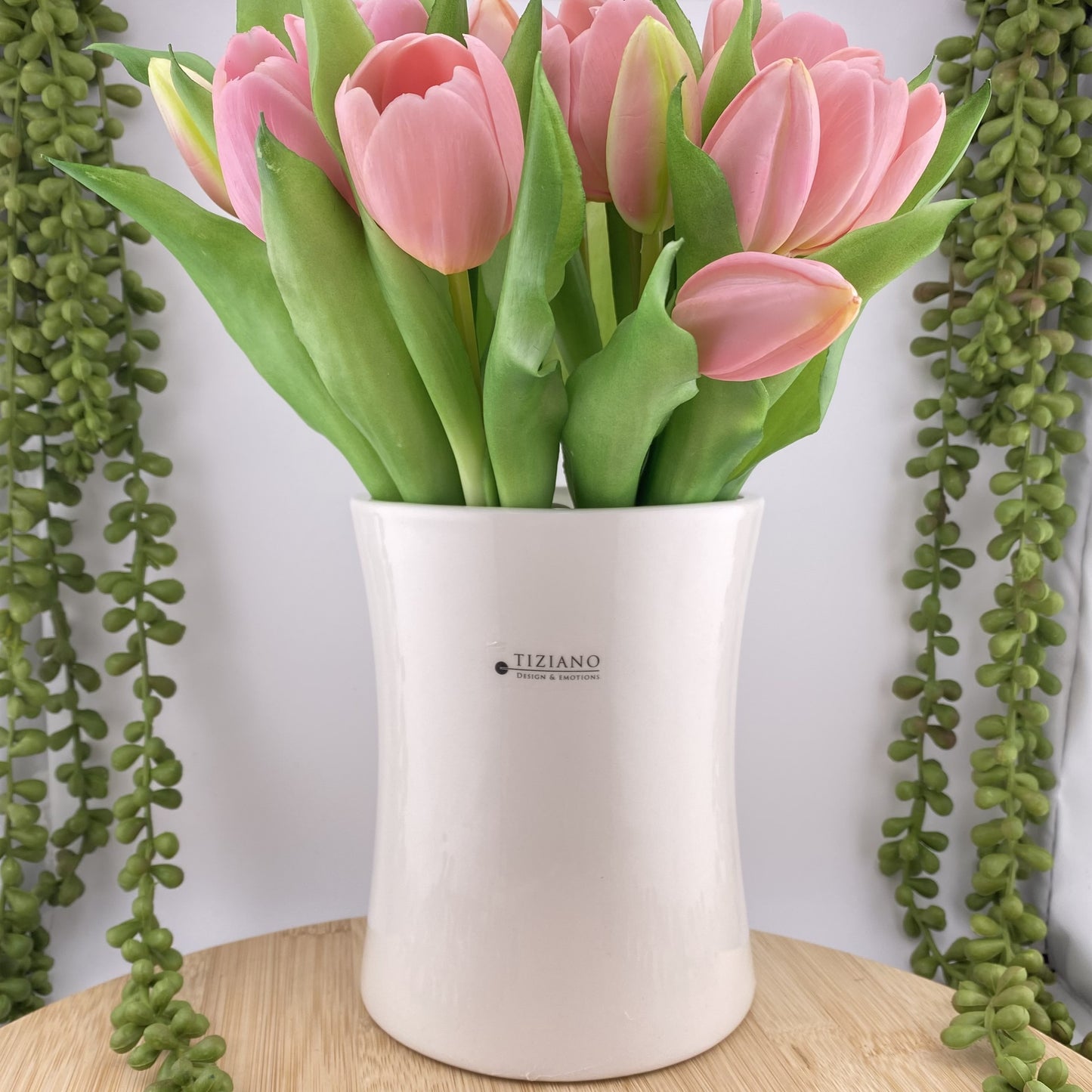 Eine zeitlose Keramikvase in creme-weißer Farbe und mit einer Höhe von 15cm ist mit pinken Tulpen im Ambiente platziert.