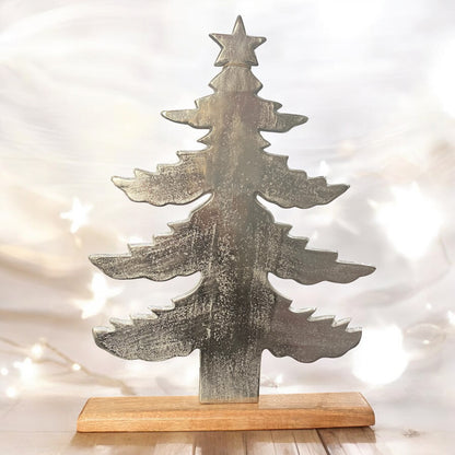 Ein Deko Tannenbaum mit Sternenspitze aus Aluminium auf einem Holzsockel im Ambiente