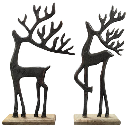Zwei stilisierte Hirschfiguren aus dunklem Material mit großen Geweihen stehen auf rechteckigen Holzsockeln vor weißem Hintergrund.