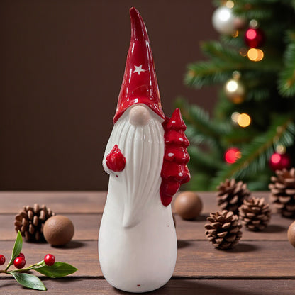 Ein großer Keramik-Wichtel mit roter Mütze und Tannenbaum in der Hand steht dekorativ auf einem Tisch vor weihnachtlicher Hintergrundbeleuchtung.