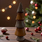 Ein glänzender Keramik-Tannenbaum in Braun steht auf einem Holztisch vor einem weihnachtlich dekorierten Raum mit Tannenzweigen und Kugeln.