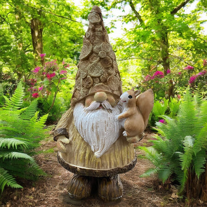 Goldener Wichtel mit Eichhörnchen auf dem Arm, detailreiche Dekofigur mit langem Bart im Naturambiente.