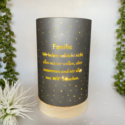 Eine taupe-farbende LED Säule mit Holzsockel. Auf dem Dekolicht ist der Spruch "Familie Wir haben vielleicht nicht alles was wir wollen, aber zusammen sind wir alles was wir brauchen" zu sehen. Das Deko Lichter ist 15cm groß und im Ambiente abgebildet.