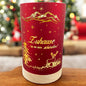 Kleines rotes Deko-Licht mit goldener Aufschrift „Zuhause ist es am schönsten!“ und leuchtender Weihnachtslandschaft vor festlich geschmücktem Hintergrund.