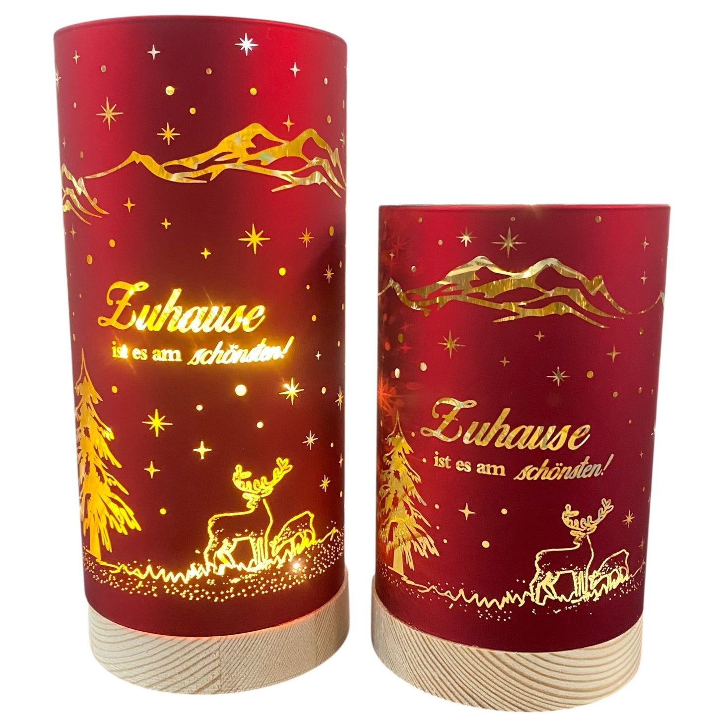 Zwei rote Deko-Lichter mit goldener Winterlandschaft und dem Schriftzug „Zuhause ist es am schönsten!“, auf hellem Holzsockel
