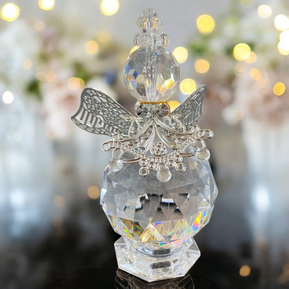 Eine gläserne Deko-Engelfigur mit facettiertem Körper und silberfarbenen Flügeln sowie filigranen Verzierungen in unterschiedlichen Größen im Ambiente
