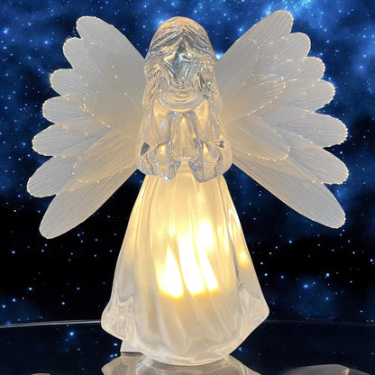 Eine transparente Acryl-Engelfigur mit Flügeln und warmweißer Beleuchtung betend im Ambiente