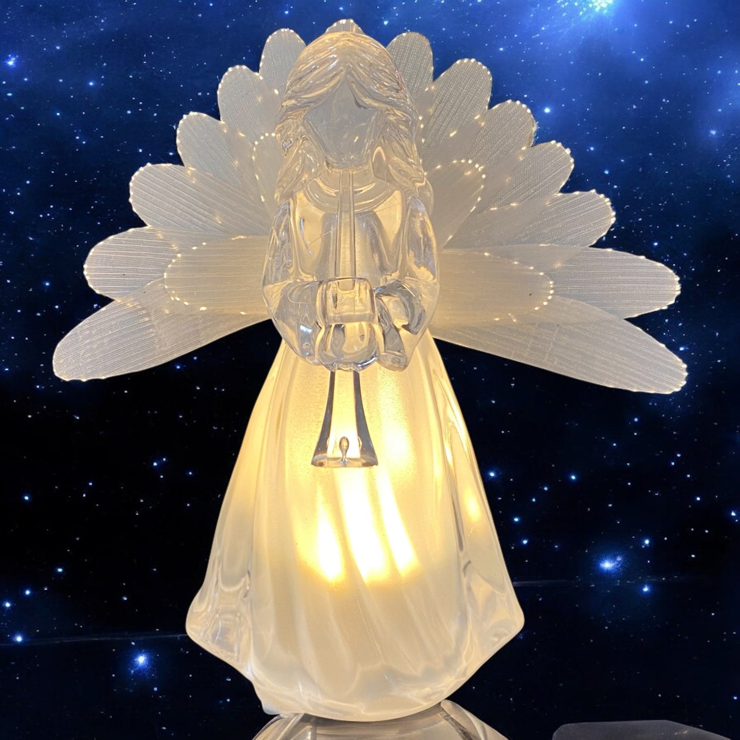 Eine transparente Acryl-Engelfigur mit Flügeln und warmweißer Beleuchtung, mit  Trompete in den Händen im Ambiente