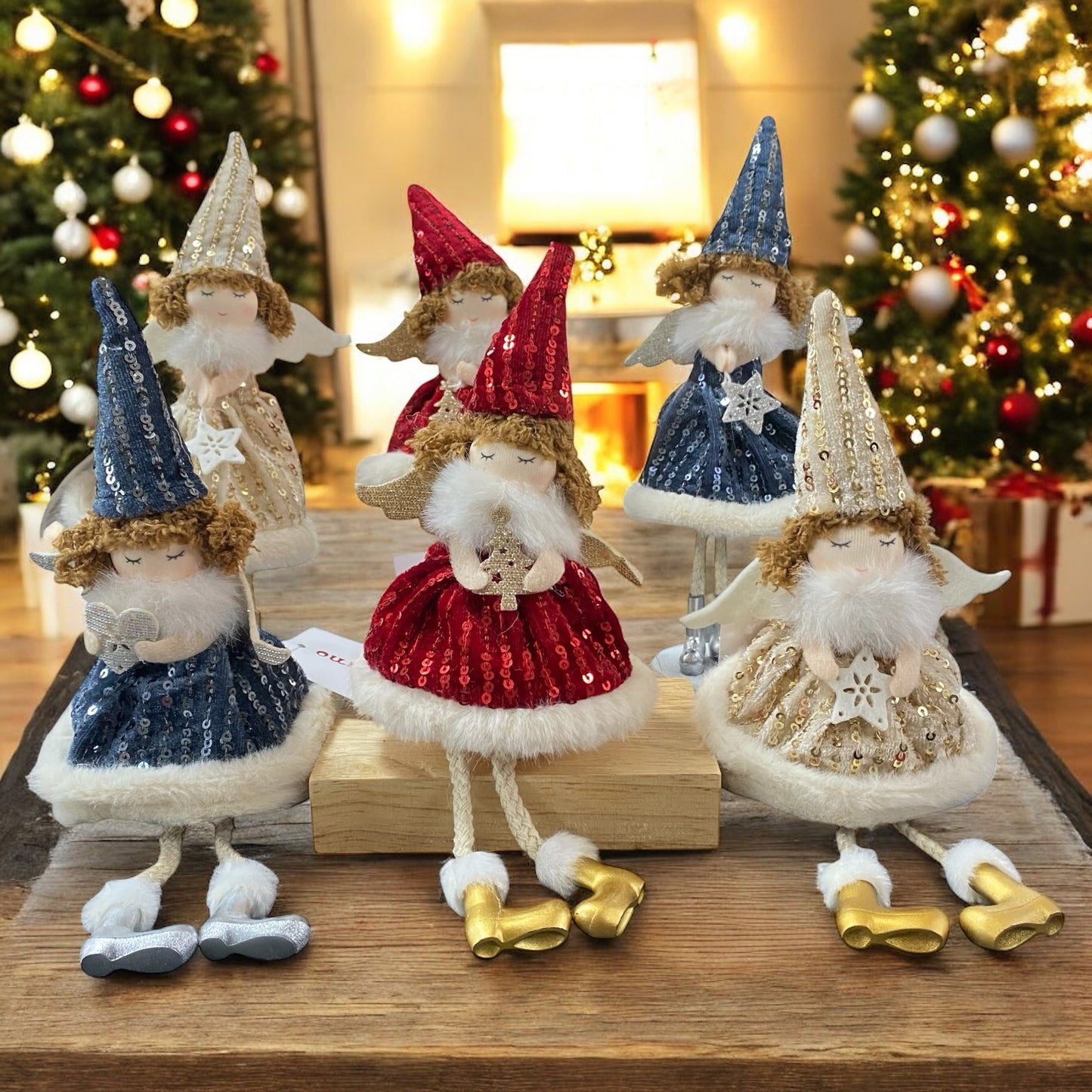 Sechs Stoff-Engelfiguren mit glitzernden Kleidern und spitzen Mützen in den Farben Gold, Rot und Blau, teils sitzend, teils stehend, mit kleinen Flügeln und goldenen oder silbernen Schuhen im Ambiente