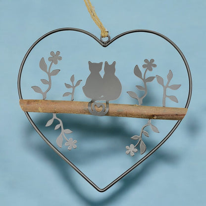 Ein Dekohänger aus einem Metall-Herz mit Katzenpaar und Holzstange als Fensterdekoration zum Aufhängen im Ambiente
