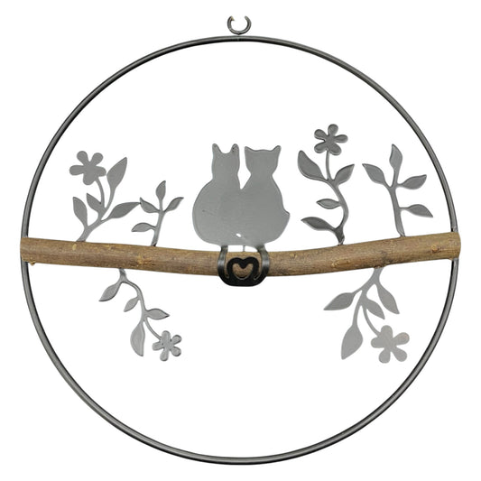 Ein Dekohänger aus einem Metall-Kreis mit Katzenpaar und Holzstange als Fensterdekoration zum Aufhängen vor weißem Hintergrund.