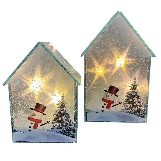 Zwei weihnachtliche Glaslichthäuser mit Schneemann- und Tannenbaum-Motiv, beleuchtet mit warmem LED-Licht.