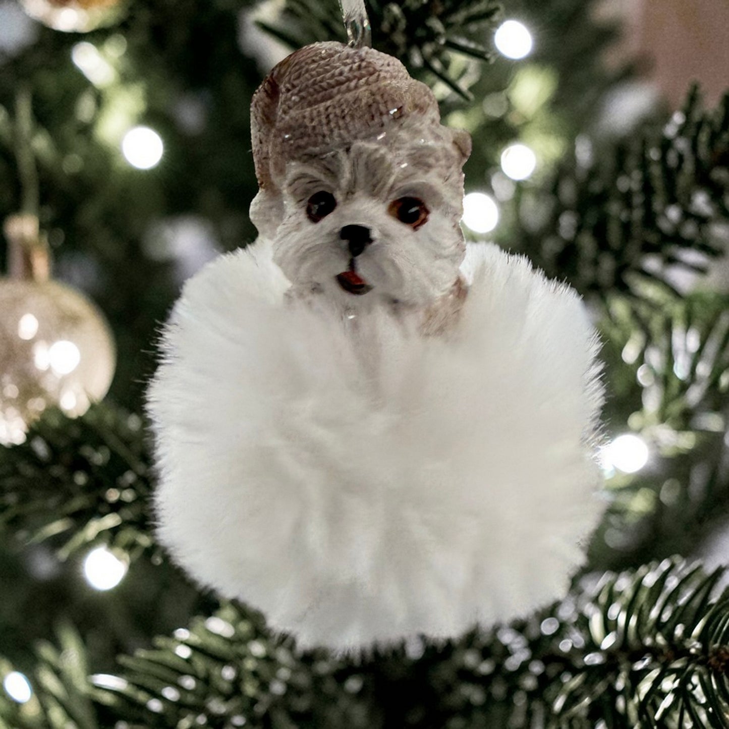 Ein Hunde-Anhänger auf flauschiger Wolke wird stimmungsvoll vor Weihnachtsbeleuchtung präsentiert.