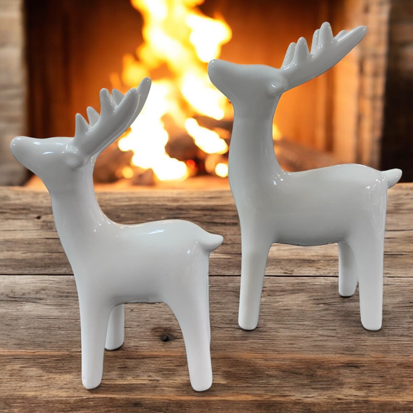 Zwei Keramikhirsche in Cremeweiß als elegante Dekofigur vor gemütlich beleuchtetem Hintergrund arrangiert.