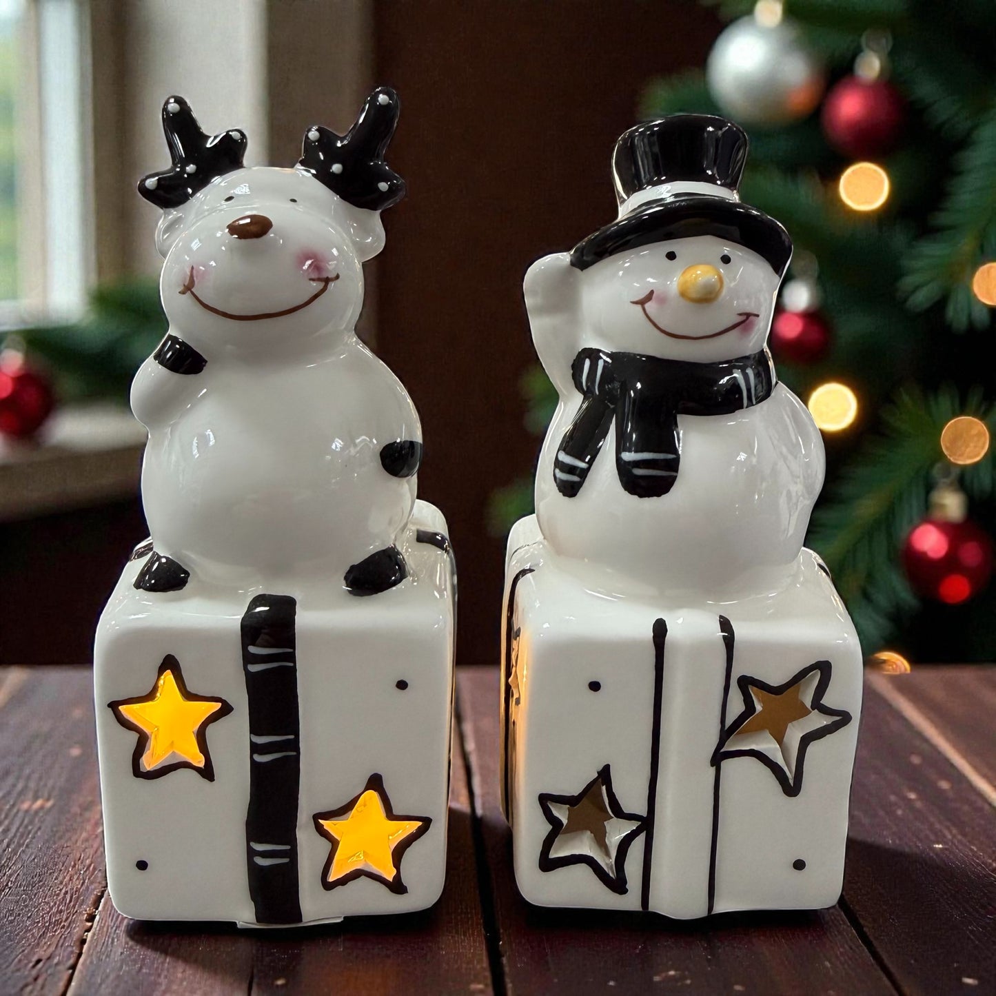 Keramik-Rentier und Keramik-Schneemann auf Geschenken mit sichtbarer LED-Beleuchtung in den Stern-Aussparungen.