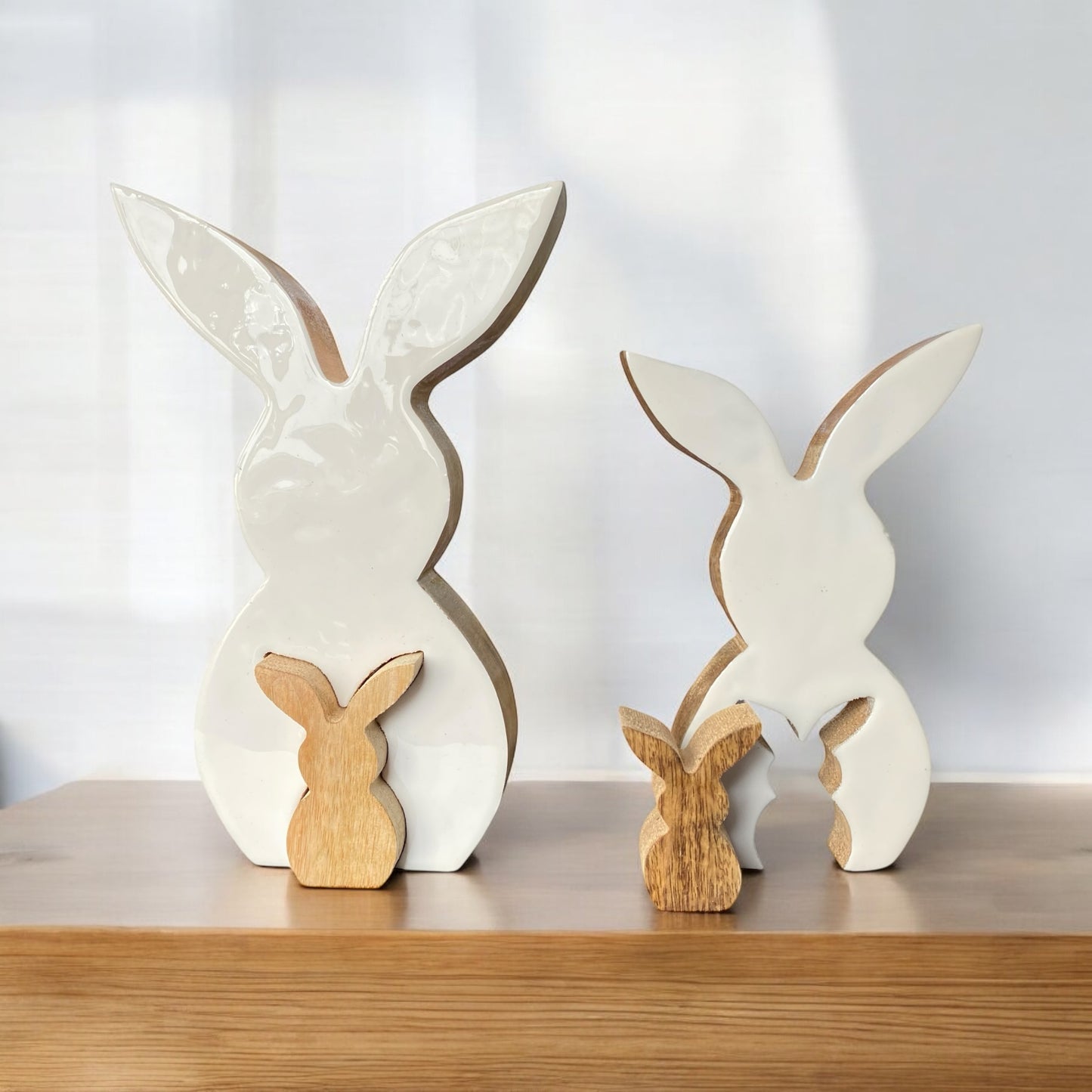 Zwei Oster-Dekoartikel in Hasenform aus Holz. Ein großer weißer Osterhase mit weißem Keramik Überzug, worin ein kleiner Holz Osterhase zu sehen ist, im Ambiente