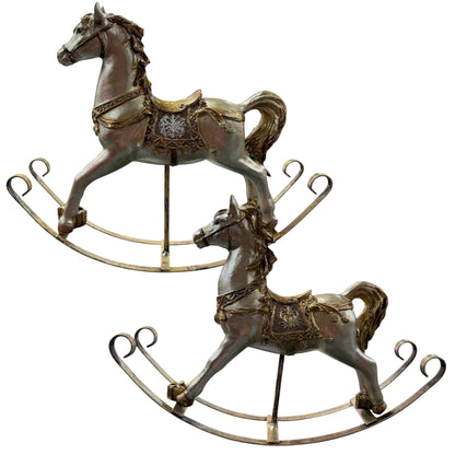Zwei dekorative Schaukelpferde in gold-champagnerfarbenem Vintage-Design mit verzierten Sätteln stehen auf gebogenen Metallkufen vor neutralem Hintergrund.