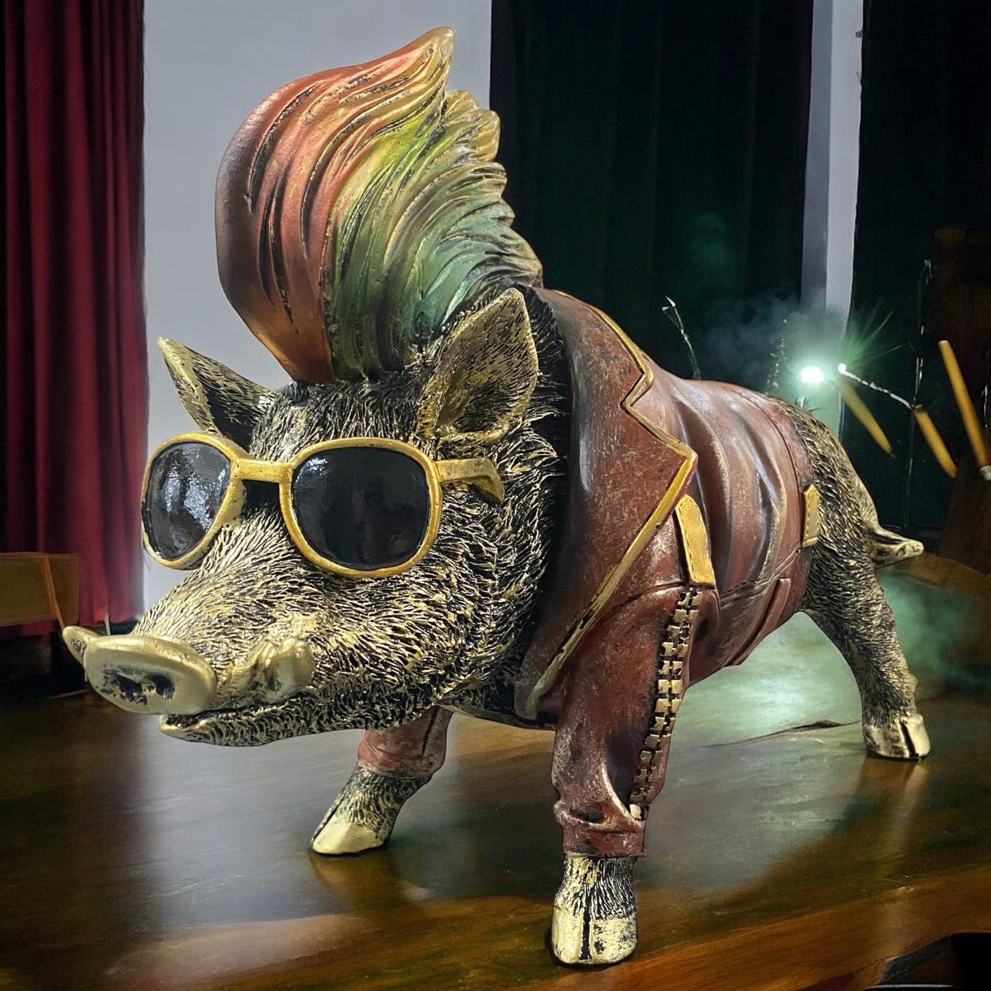 Moderne Wildschwein-Skulptur mit Sonnenbrille und Lederjacke, stilvoll auf Tisch vor rotem Vorhang dekoriert.
