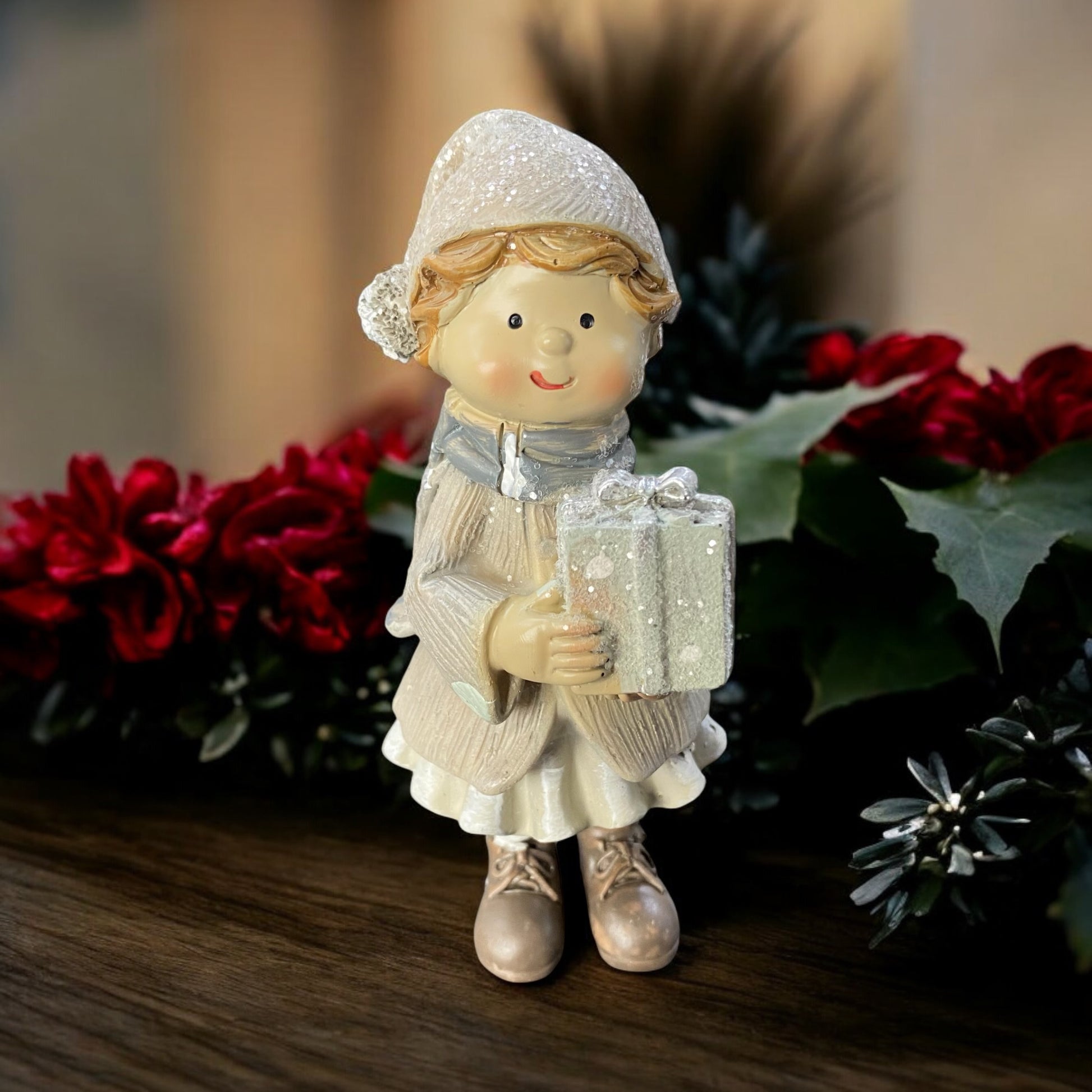 Winterkind Mädchen mit Geschenk in der Hand im Ambiente platziert