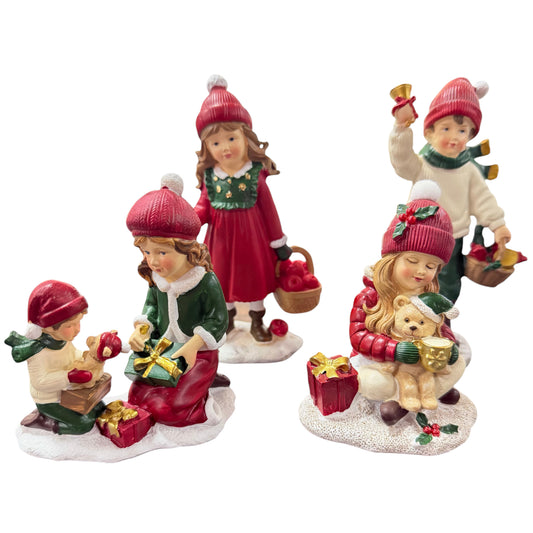 Mehrere dekorative Kinderfiguren in winterlicher Kleidung mit roten Mützen sind in unterschiedlichen Szenen mit Geschenken und Accessoires dargestellt.