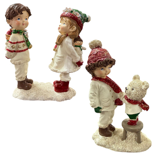 Zwei dekorative Figuren zeigen ein Kind, das ein Geschenk hinter dem Rücken hält, gegenüber einem anderen Kind.