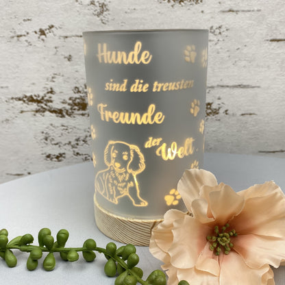 Eine silberne LED Säule mit Holz Sockel. Auf dem Dekolicht ist ein Hund und der Spruch "Hunde sind die treusten Freunde der Welt" abgebildet in goldener Schrift. Das Dekolicht ist beleuchtet im Ambiente platziert.